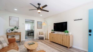 Ein stilvolles Wohnzimmer mit Sofa, Couchtisch, Fernseher und Deckenventilator.