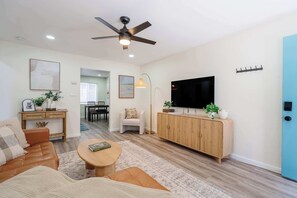 Ein stilvolles Wohnzimmer mit Sofa, Couchtisch, Fernseher und Deckenventilator.
