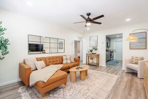 A modern living room with a sectional sofa, a coffee table, and a ceiling fan. - Coastal 2BR | Walk to Ocean Beach & Cafés (San Diego)