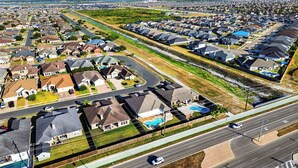 An aerial view of a residential area with houses, a road, and a swimming pool. - Graceland by Avantstay Private Pool + Spa + Fenced Backyard Near North Padre Island (Corpus Christi)