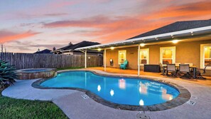 A backyard with a swimming pool, a covered patio area, and a wooden fence. - Graceland by Avantstay Private Pool + Spa + Fenced Backyard Near North Padre Island (Corpus Christi)