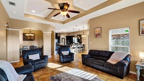 A spacious living room with a ceiling fan, leather sofas, and a dining area in the background. - Graceland by Avantstay Private Pool + Spa + Fenced Backyard Near North Padre Island (Corpus Christi)
