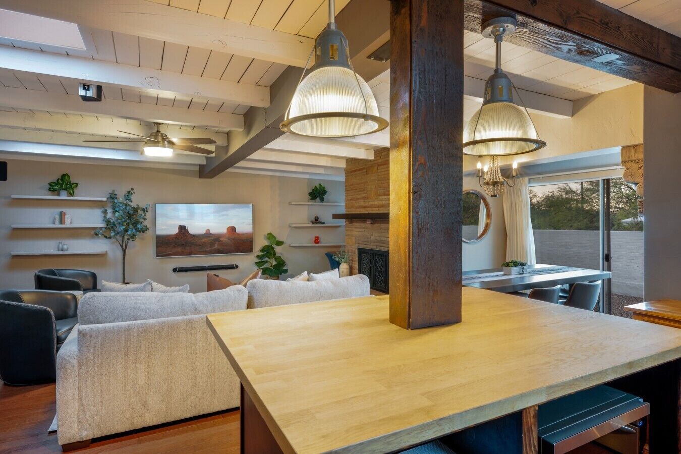 Ein modernes Wohnzimmer mit einem Holzesstisch, Sofas und Pendelleuchten.