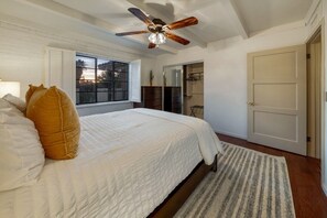 Ein Schlafzimmer mit einem Bett, einem Deckenventilator, einem Fenster und einer Tür.