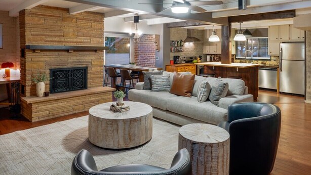 Een moderne woonkamer met een open haard, een bank, een salontafel en een eetgedeelte met stoelen.
