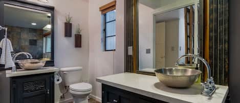 Un baño con un espejo grande, un lavabo, un inodoro y una ventana con vistas.