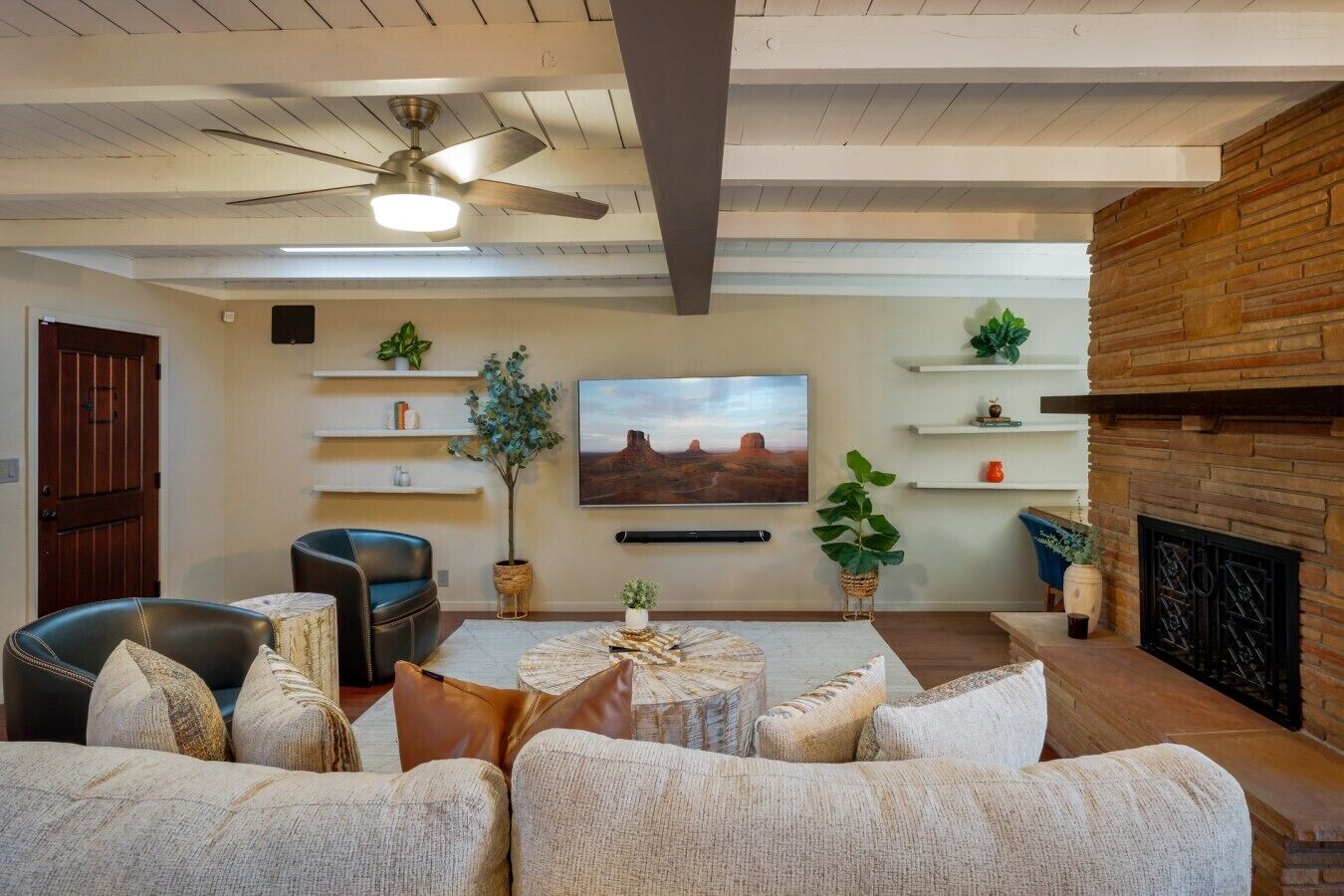 Un salon avec une cheminée, un ventilateur de plafond et un téléviseur fixé au mur.