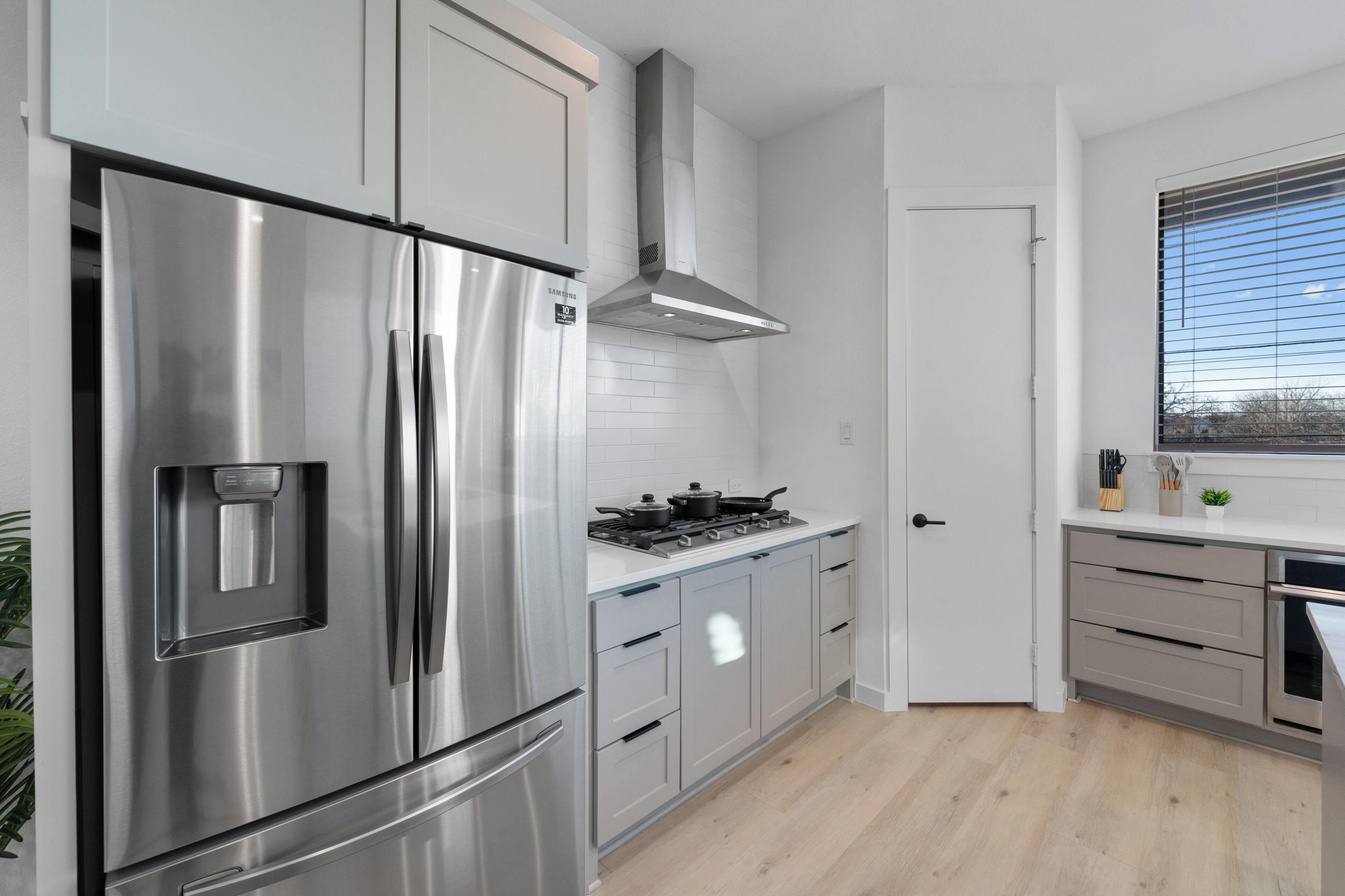 Une cuisine moderne dotée d’appareils électroménagers en acier inoxydable, d’une cuisinière à gaz et de meubles de rangement de couleur claire.