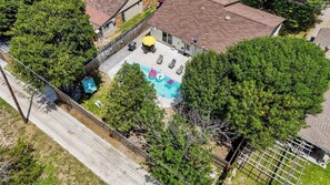 Vista aérea de um quintal residencial com piscina, móveis de pátio e área cercada.
