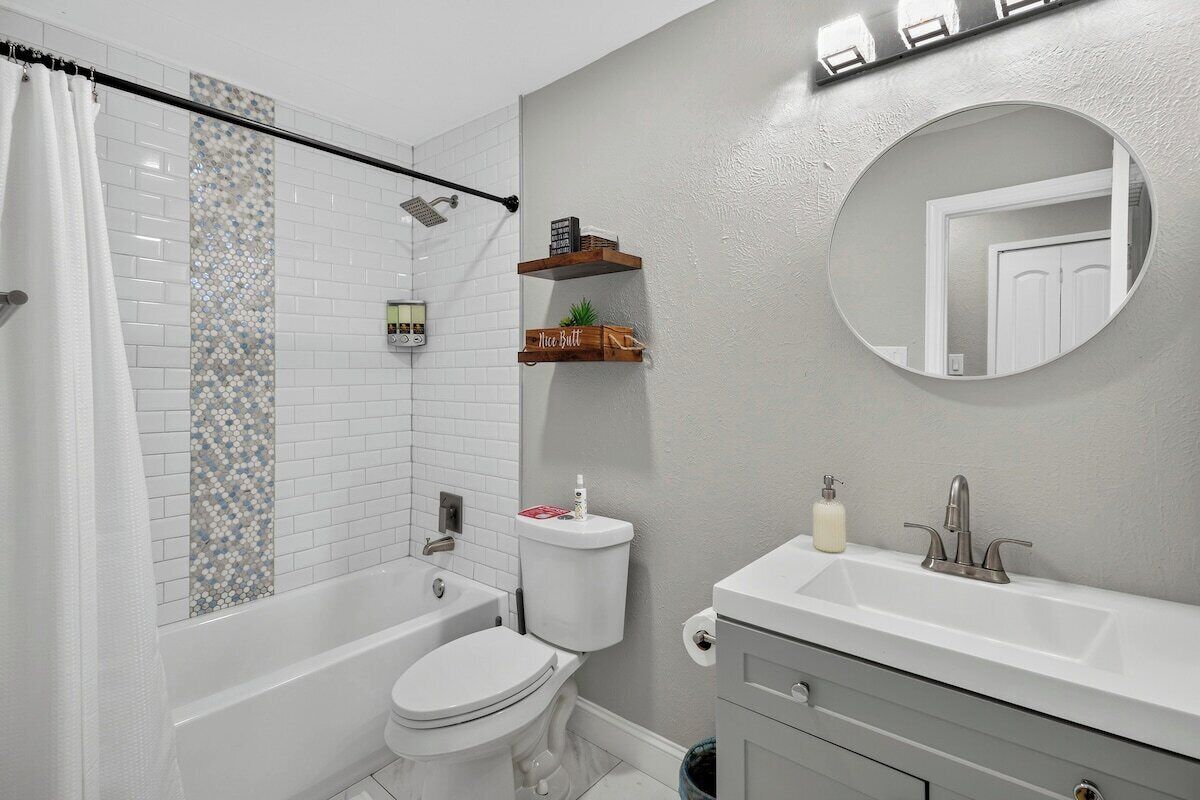 Un bagno con vasca, WC e lavandino con specchio soprastante.