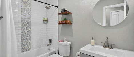 Un bagno con vasca, WC e lavandino con specchio soprastante.