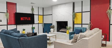 A modern living room with a fireplace, a flat-screen TV, and a sofa.