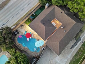 An aerial view of a residential property with a swimming pool, patio furniture, and a covered outdoor area. - Home Theater - Game Room - Pool - Hot Tub - Golf (Plano)
