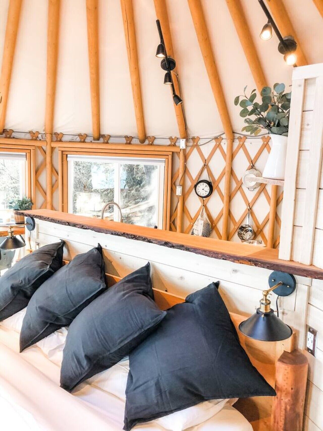 Une pièce confortable avec un lit, un plafond en bois, une fenêtre et une horloge fixée au mur.