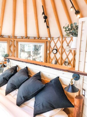 A cozy room with a bed, a wooden ceiling, a window, and a wall-mounted clock. - The Trincomali Hideaway Oceanfront Yurt (Salt Spring Island)