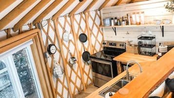 A compact kitchen with wooden beams, a stove, oven, and a sink.