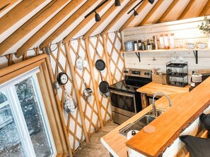 A compact kitchen with wooden beams, a stove, oven, and a sink.