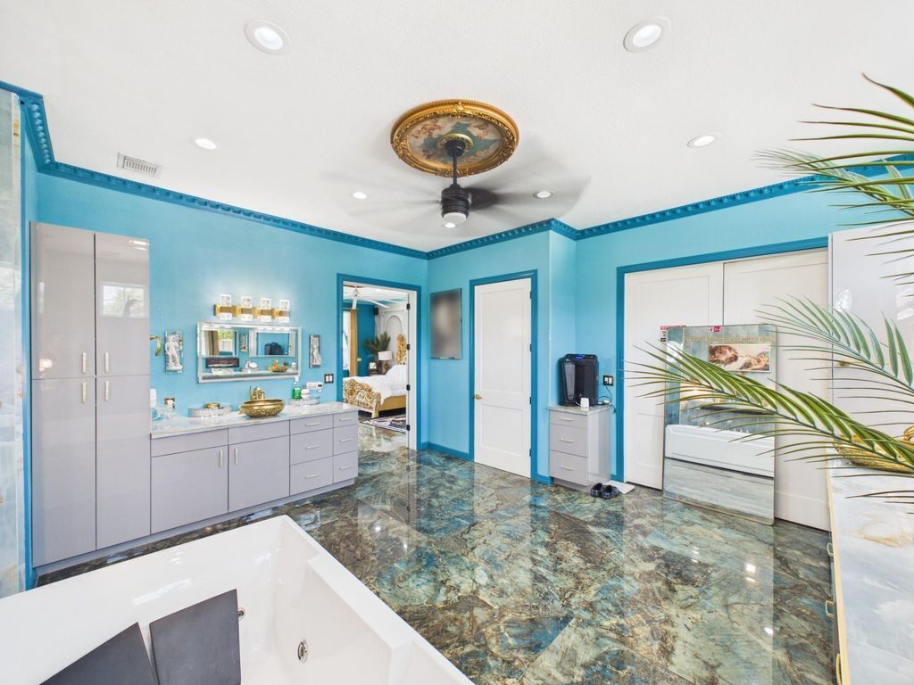 A bathroom with a white bathtub, a vanity with a mirror, and a ceiling fan.