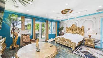 A luxurious bedroom with a large bed, a round table, and a view of the outdoors.