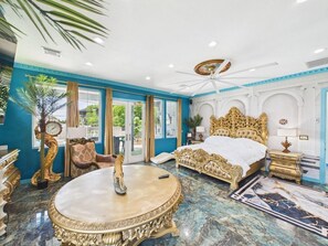 Une chambre à coucher luxueuse, dotée d’un grand lit, d’une table ronde et offrant une vue sur l’extérieur.