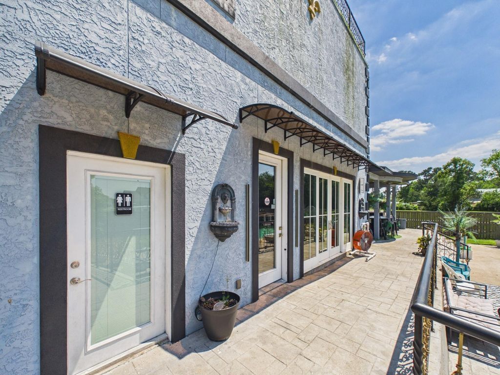 A building with a textured facade, a door with a wheelchair symbol, and a covered outdoor seating area.
