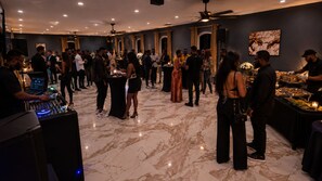 Un esdeveniment social amb gent relacionant-se en una sala amb sòcols de marbre i un espai per a DJ.