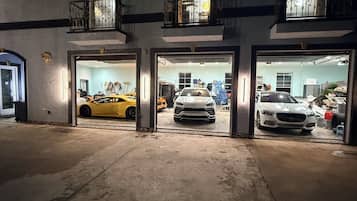 En byggnad med tre garageportar, där varje port leder in till en separat bil.