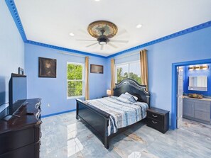 A bedroom with a bed, bedside tables, a ceiling fan, and a window.
