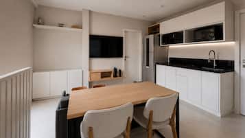 Una cocina moderna con armarios blancos, una mesa de comedor de madera y dos sillas.