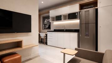 Uma cozinha moderna com eletrodomésticos embutidos, uma área de jantar com mesa e cadeiras, e uma TV de tela plana fixada na parede.