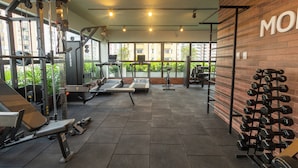 Un gimnasio con diverso equipo de ejercicio, incluyendo cintas de correr, máquinas de pesas y mancuernas.