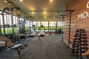 Uma academia com diversos equipamentos de exercícios, incluindo esteiras, aparelhos de musculação e halteres.