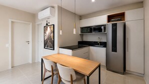 A modern kitchen with a built-in microwave, a stainless steel refrigerator, and a wooden dining table with chairs.