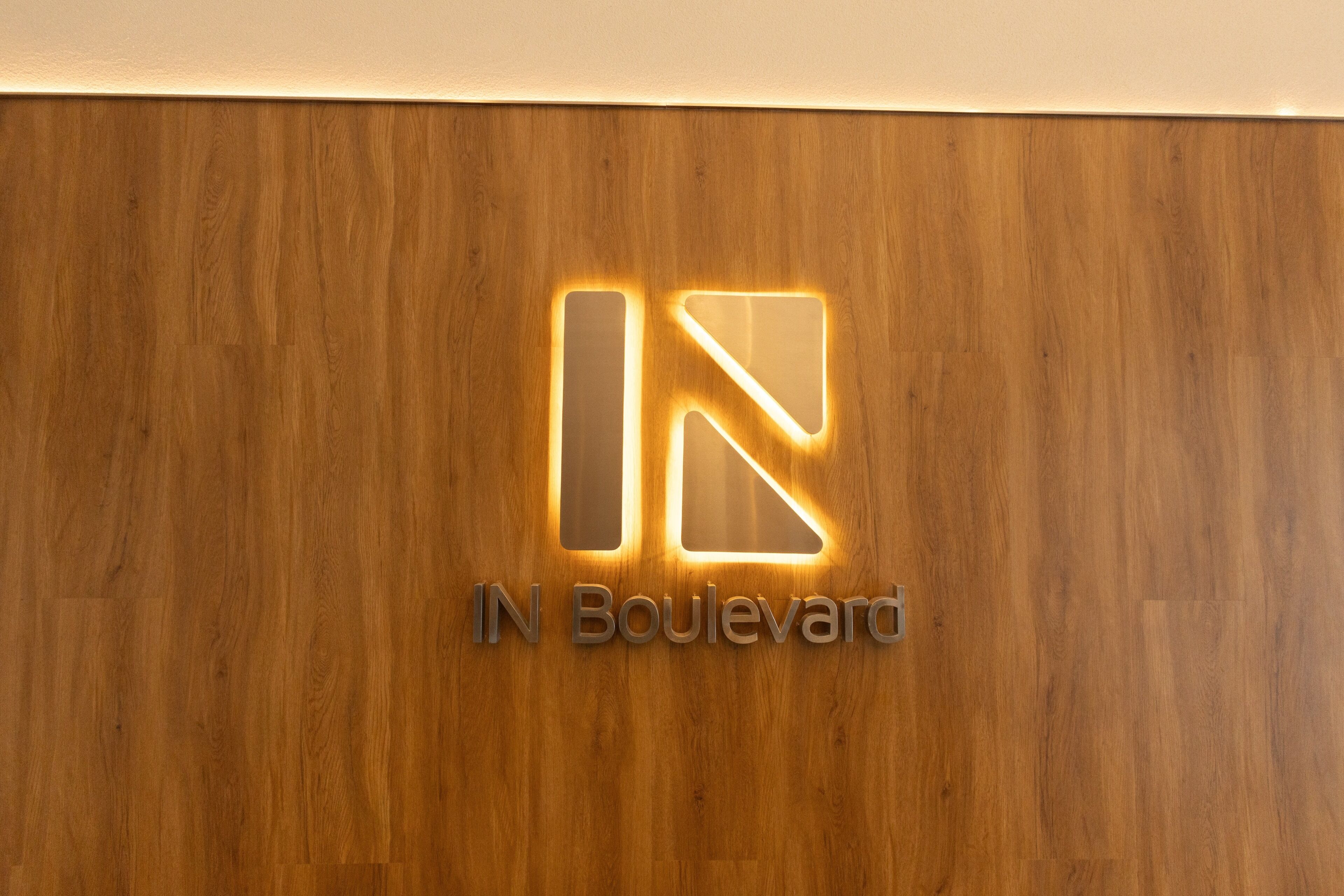Eine Holzverkleidung mit einem Logo und der leuchtenden Aufschrift 'IN Boulevard'.