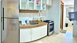A modern kitchen with a stainless steel refrigerator, a built-in oven, a granite countertop, and white cabinetry. - Vacanze - Maceió Facilities (Maceió)