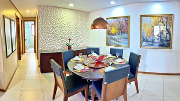 Un comedor con una mesa redonda dispuesta para seis personas, rodeada de sillas, una pared con textura y cuadros en la pared.
