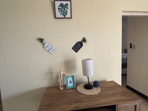 Ein Zimmer mit einem Holztisch, einem gerahmten Bild, einer kleinen Pflanze und zwei an der Wand befestigten Schildern.