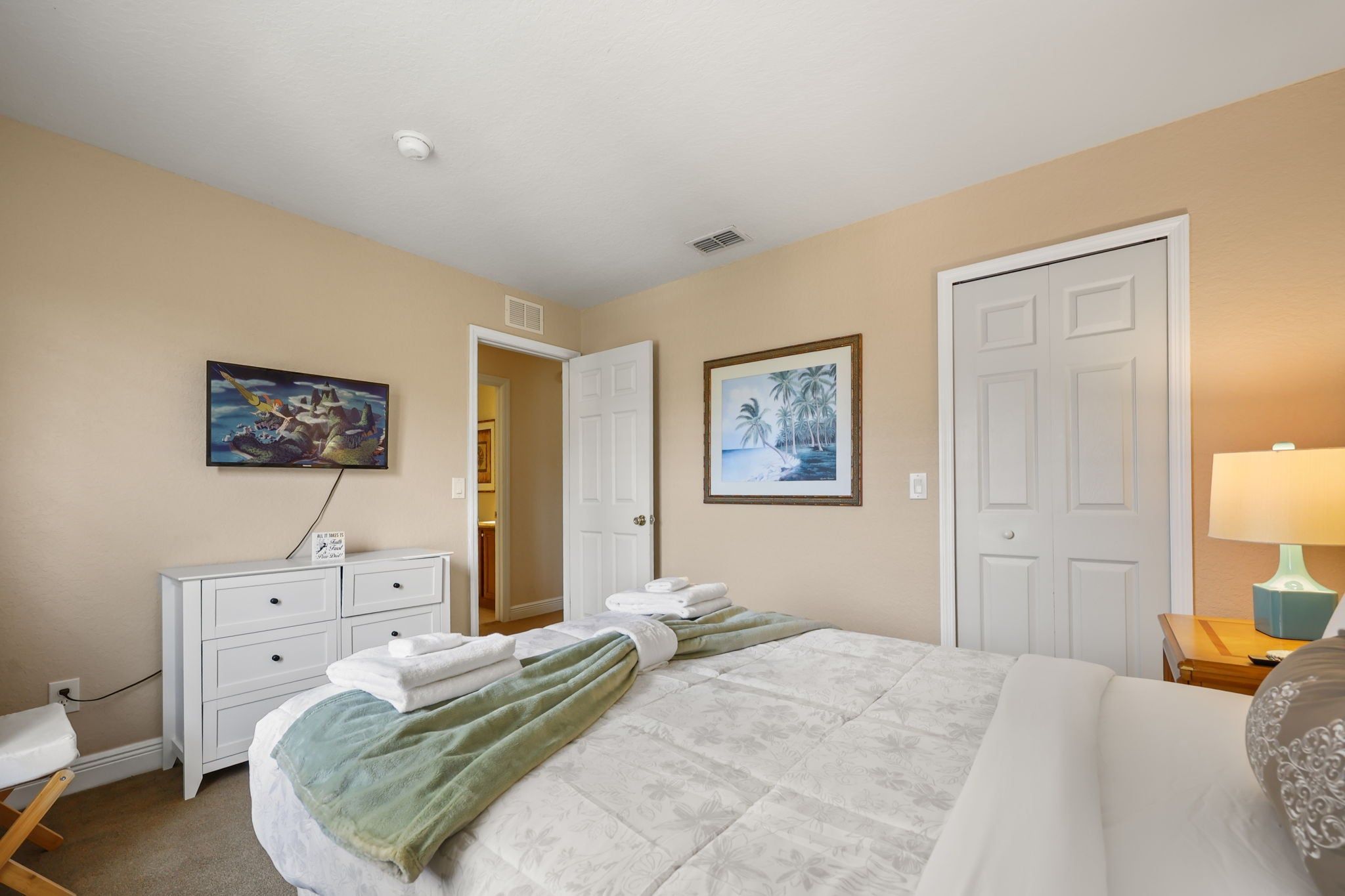 Une chambre d’hôtel avec un lit, un bureau, une chaise, une armoire, un tableau et une porte.