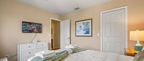 Une chambre d’hôtel avec un lit, un bureau, une chaise, une armoire, un tableau et une porte.