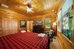 Ein Schlafzimmer einer Holzhütte mit einem Bett, einer Kommode und einem Gemälde.