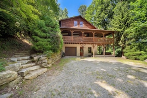 A two-story wooden cabin with a porch, surrounded by dense forest. - Mountain Getaway with Hot Tub and Game Room (Vilas)