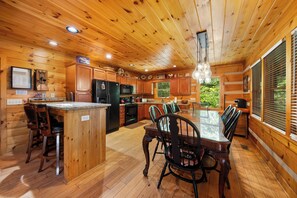 Ein Holzblockhaus-Interieur mit Küche, Essbereich und einem großen Fenster.