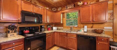 Una cocina con armarios de madera, microondas, estufa y lavavajillas.