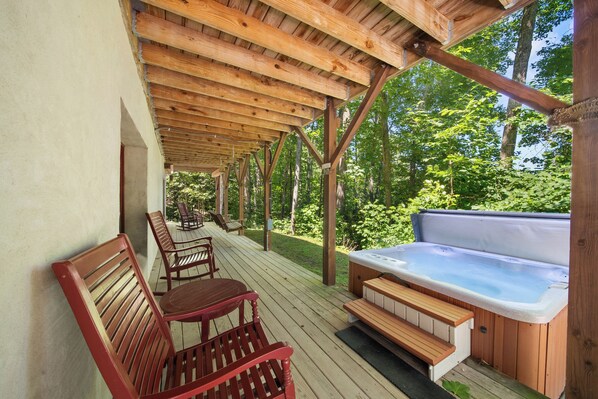 Eine Holzterrasse mit Whirlpool und Sitzgelegenheit.