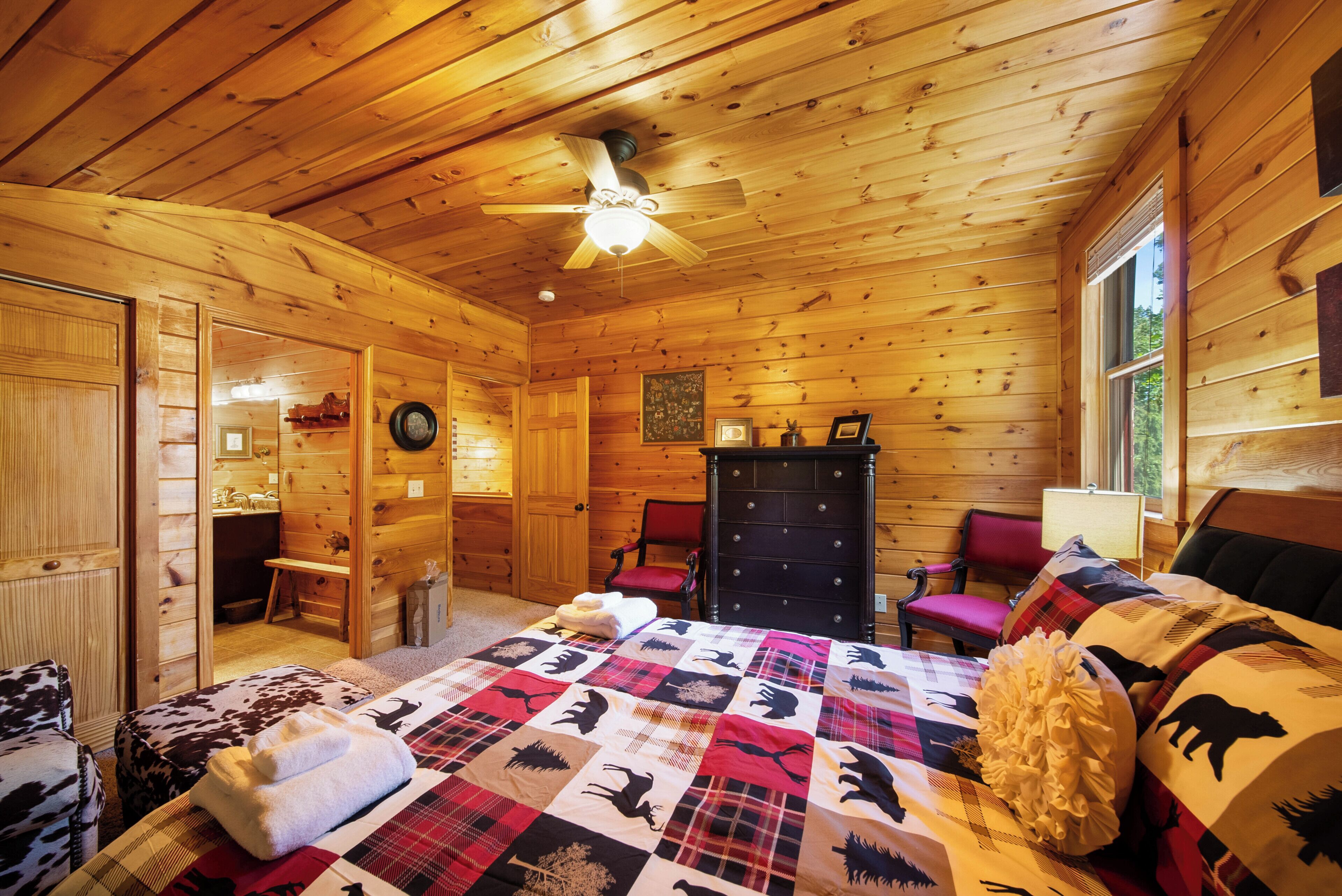 Une chambre confortable dans un chalet, avec un plafond en bois, un lit recouvert d’une courtepointe, une commode et une chaise.