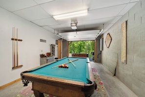 A pool table in a room with a view of trees through an open door. - Mountain Getaway with Hot Tub and Game Room (Vilas)