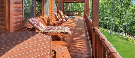 A wooden deck with outdoor seating and a view of a green landscape.