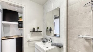 A modern bathroom with a sink, mirror, towel rack, and shower. - Victoria CHIC Studio - Downtown - Balcony with Mountain Views (Aix les Bains)