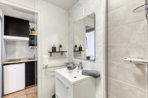 Et moderne badeværelse med vask, spejl, håndklædetørrestativ og bruser.