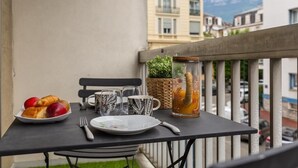 A balcony with a table set for breakfast, including croissants, apples, and a glass of orange juice. - Victoria CHIC Studio - Downtown - Balcony with Mountain Views (Aix les Bains)